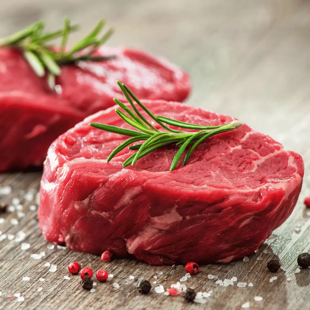 Deux morceaux de viande rouge posé sur un fond beige avec des grains de poivre et du gros sel décorés avec de l'aneth