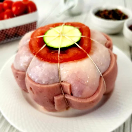 paupiette de poulet dans une assiette blanche sur un fond blanc avec des tomates cerises, des épices et du sel autour en arrière plan