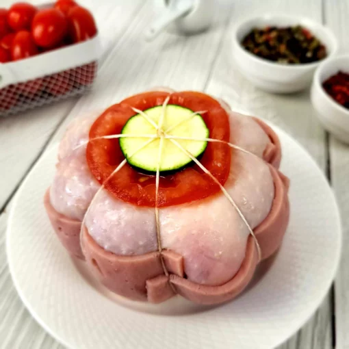 paupiette de poulet posée sur une assiette blanche sur un fond blanc avec des épices et des tomates cerises